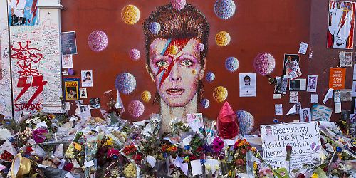 Wandgemälde von David Bowie mit Trauerbekundungen davor